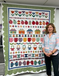 A person standing next to a quilt

Description automatically generated with medium confidence